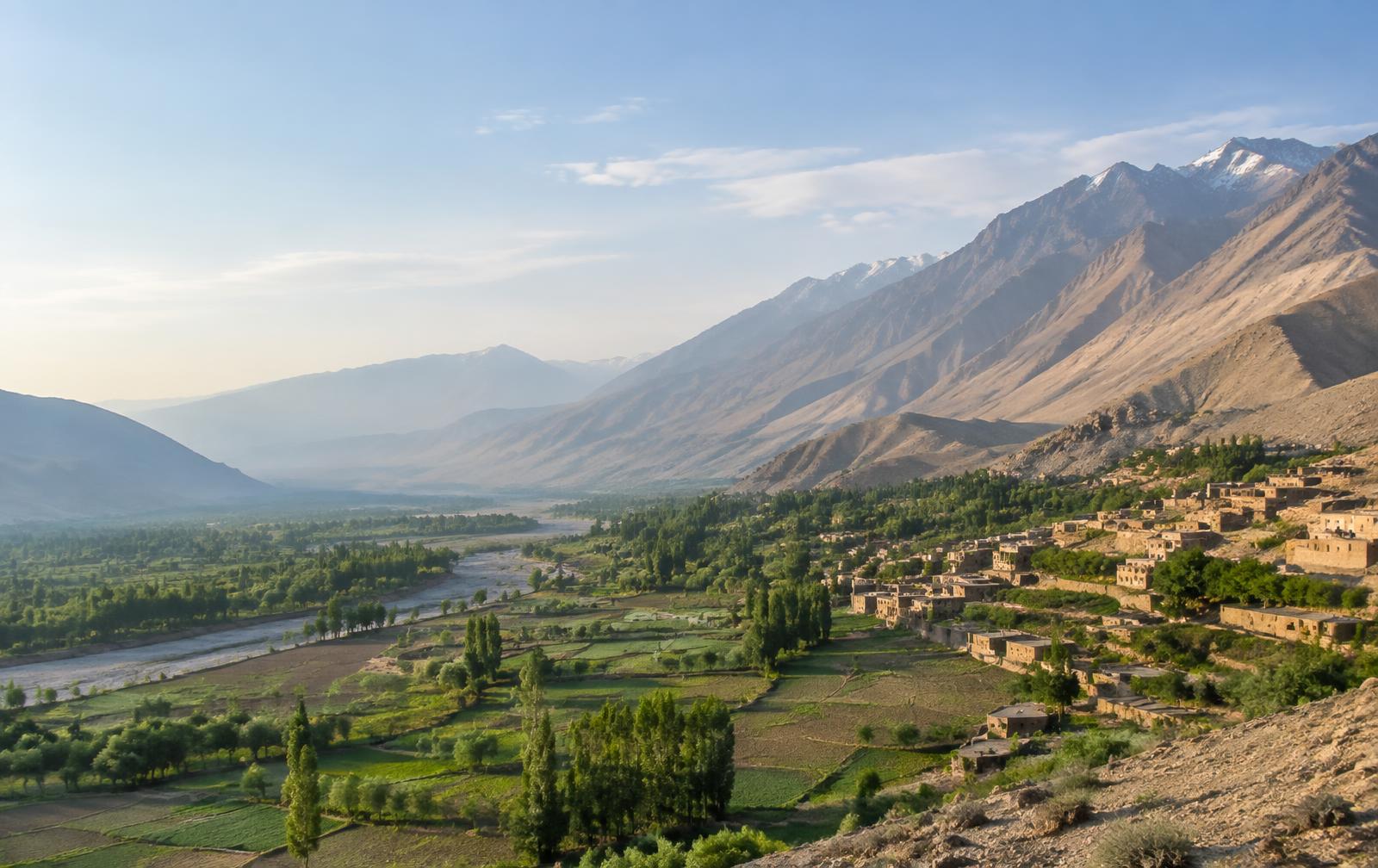 A wide Afghan mountain valley with farmland and a village
